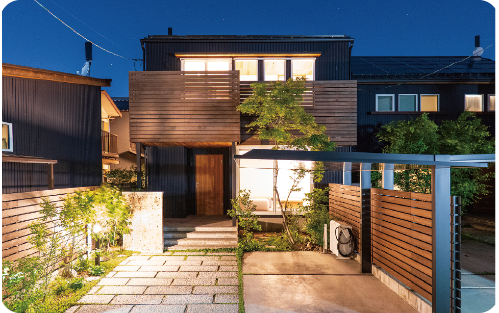 ウッドフェンスと石畳が照らされる住宅外観写真