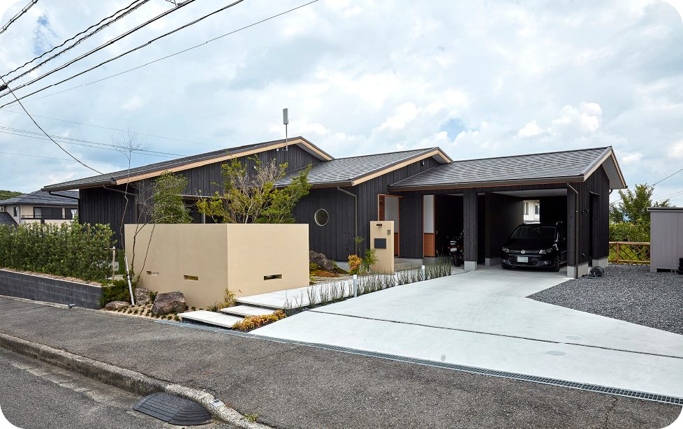 黒い外壁が特徴的な住宅と駐車スペースを備えた外観写真